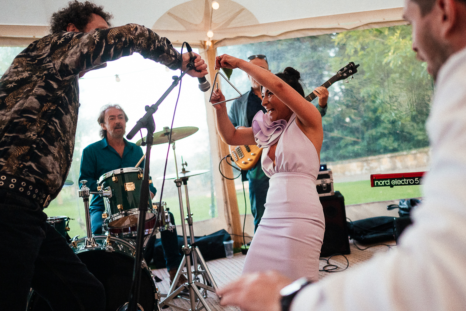 playing the triangle on the dance floor by UK documentary wedding photographer Simon Dewey