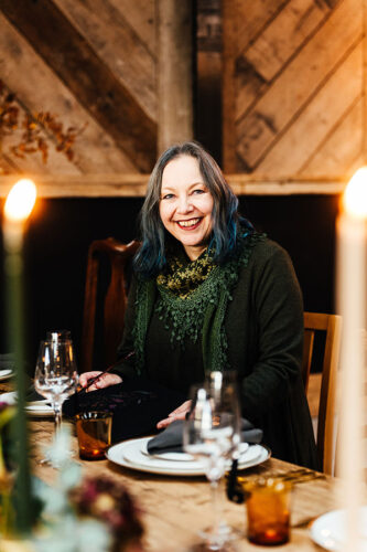 Claire smiling at the camera at Ghyll Barn where the table is set for a wedding photoshoot. By Hannah Hall Photography