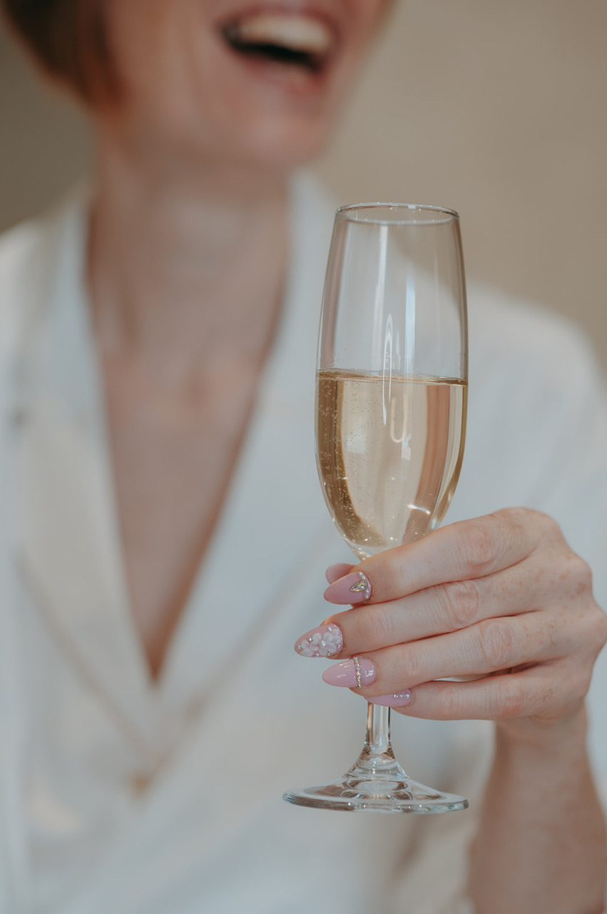 Woman holding a champagne flute with beautifully done bridal nails - by Damien Vickers Photography