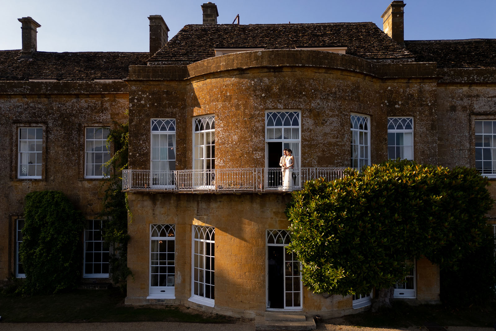 Bride and groom stood on the balcony at North Cadbury Court at golden hour - taken by Martin Dabek Photography