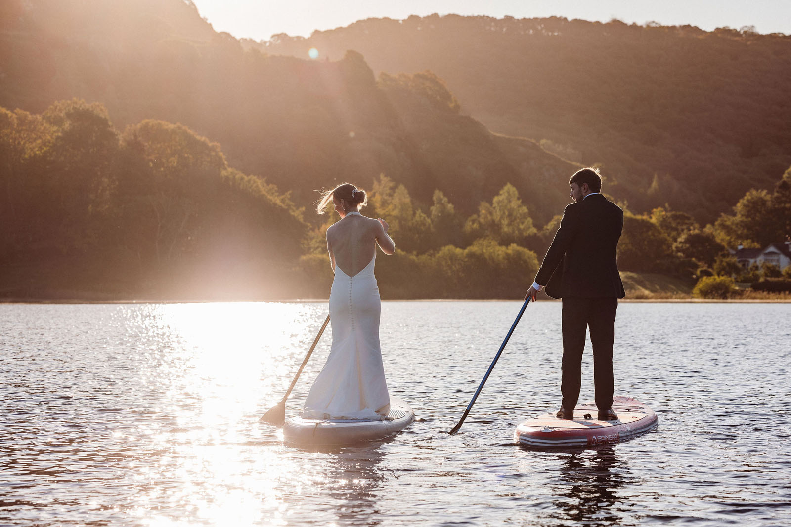 Bride and groom in full wedding dress on paddle boards in the Lake District by Mark Battista Photography