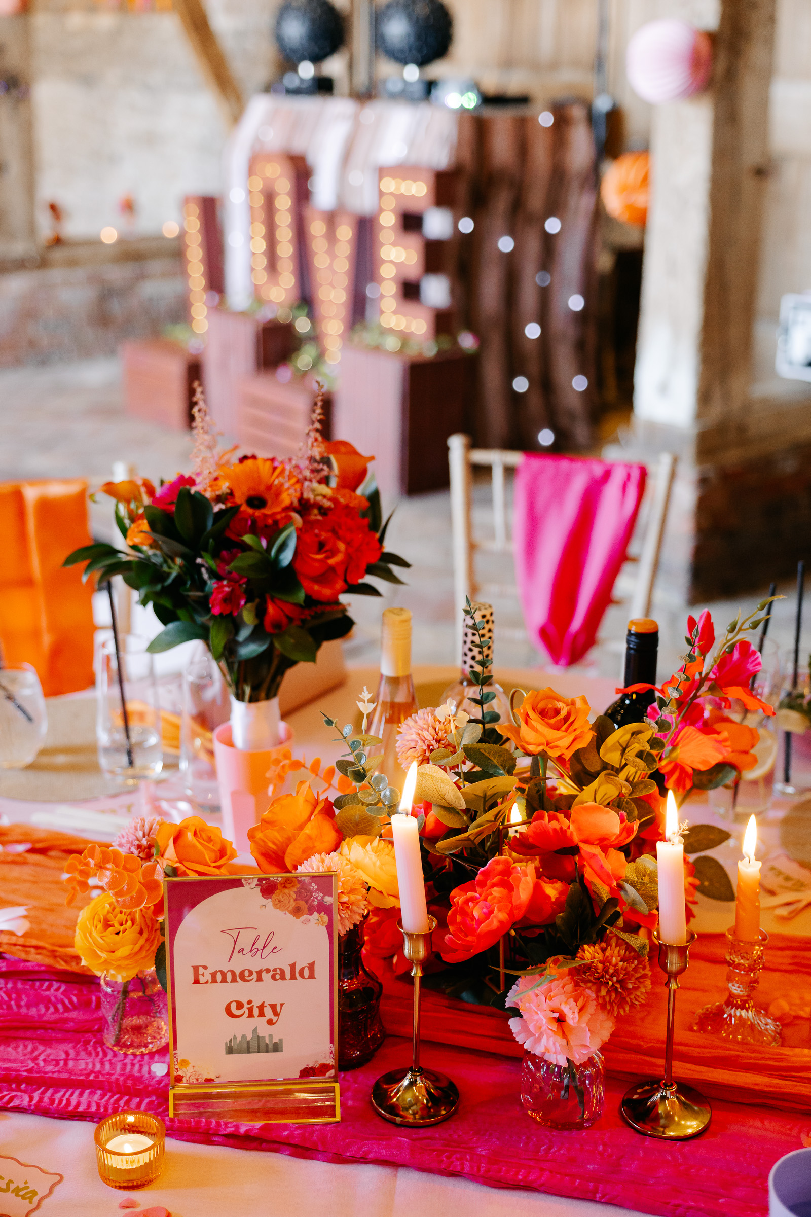 Vibrant wedding table in hot pink, orange and coral with candles and flowers | Lauren Batten Events at Stonehill Barn Oxfordshire