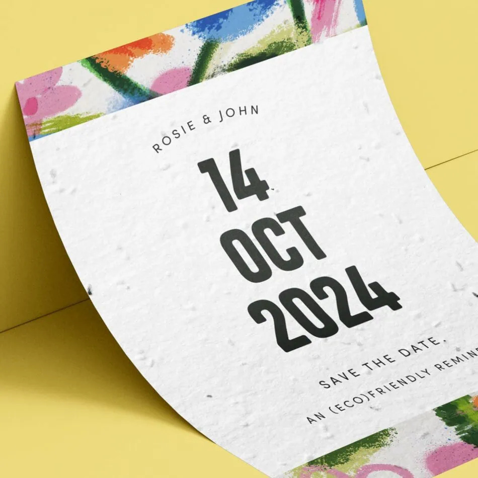 Close up of seed paper wedding Save the Date card with colourful flower border print against a yellow background | by SeedPrint UK