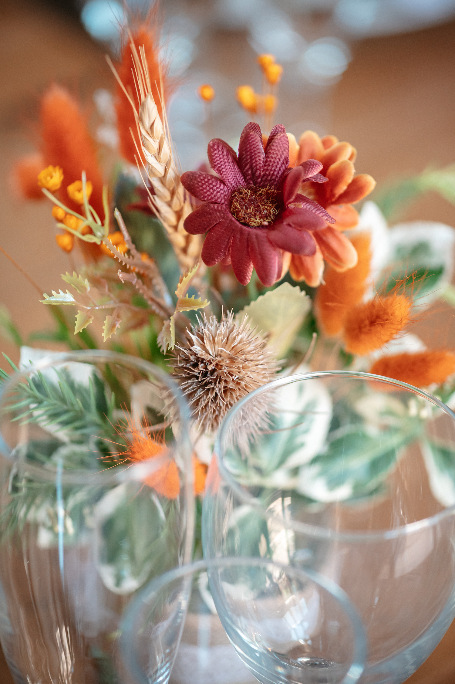 Faux silk and dried wedding flowers with glassware in autumnal colours