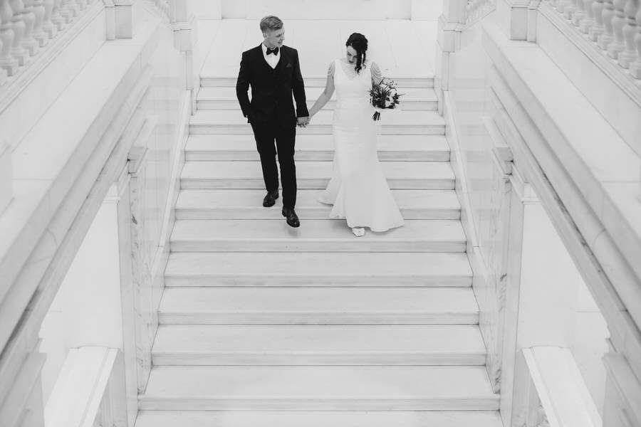 couple descending a wide open stairway on their wedding day