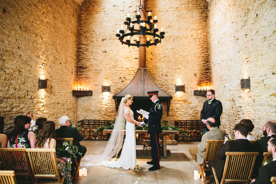 Bride and groom in military dress saying their vows in a wedding barn