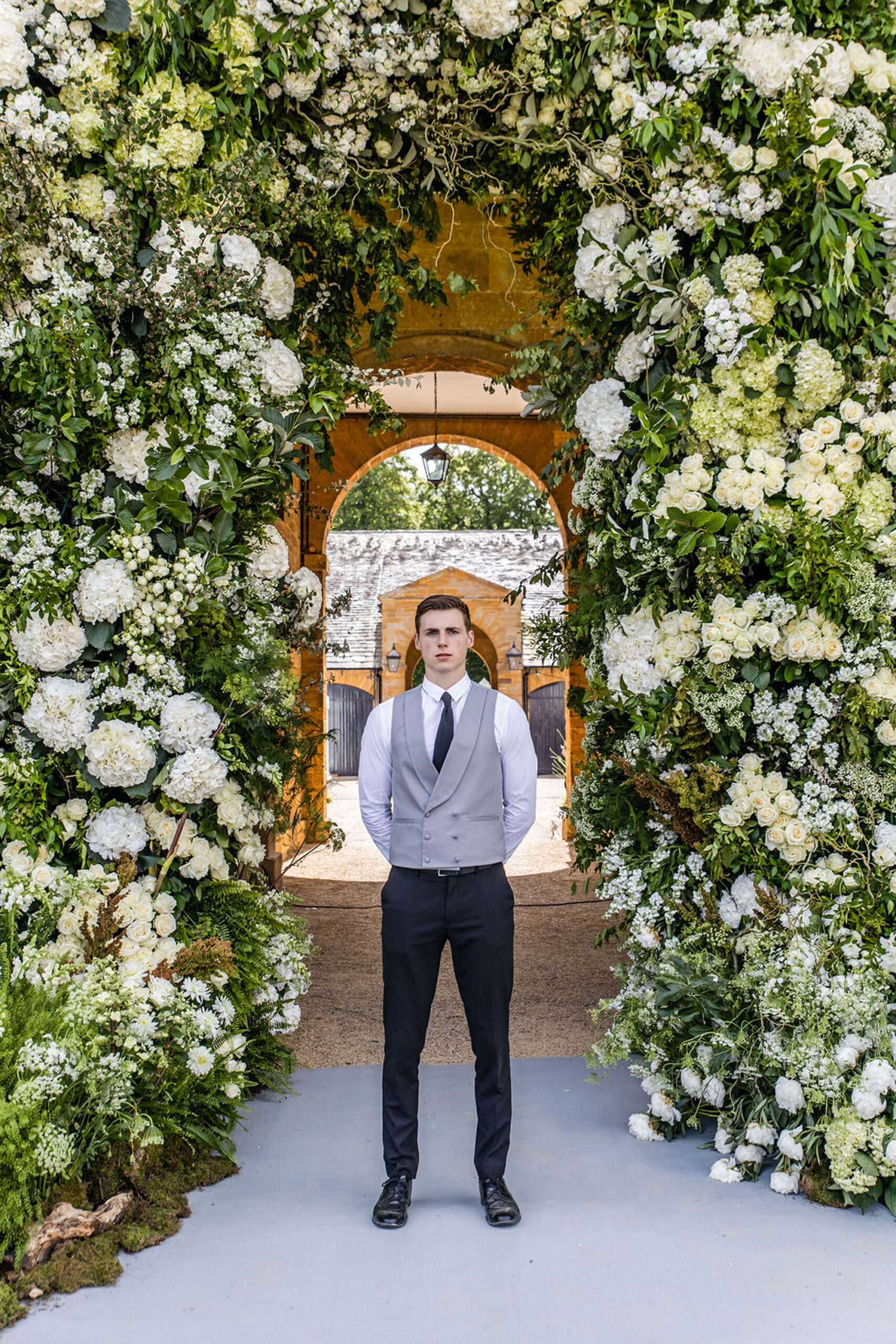 A Niemierko host stands between the pillars of an opulent floral display at the entrance to a prestigious wedding venue