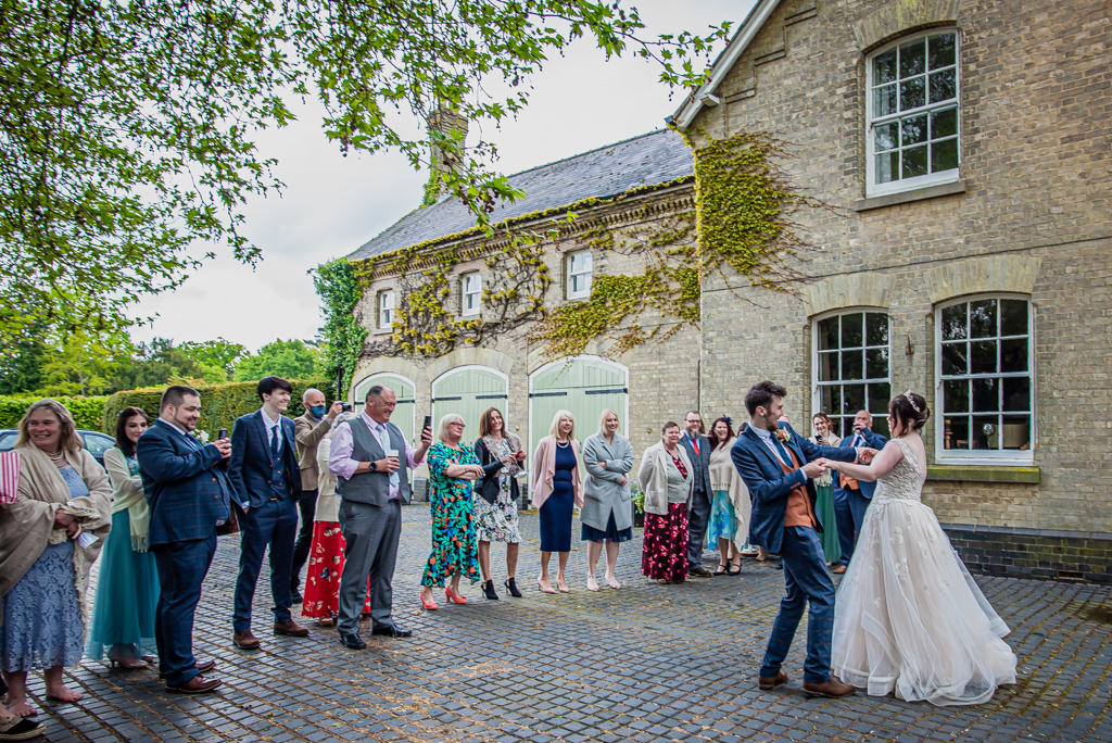 Photo of Lorna and Keanu's wedding at Stradsett Hall. The venue is quirky with lots of foliage and greenery. There are 30 guests and the couple are in a blush wedding dress and blue check suit. Photography by Damien Vickers.