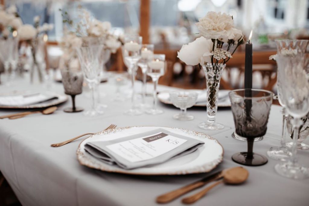 Styled wedding photoshoot with Wonderful Events on English Wedding. A bride and groom wearing black tie and white dress with all white flowers and grey tableware with smoky glass