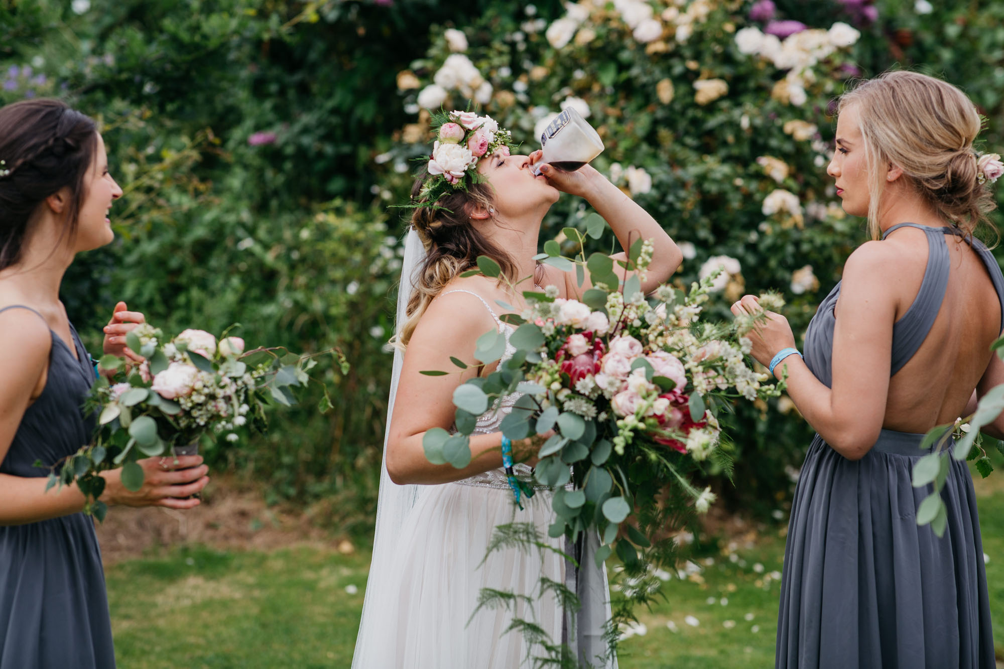 Yorkshire wedding photography of Alicia and Phil. She wears a white boho style dress and he's in a blue ckech suit. She has a full flower crown in delicate pinks, and they look happy. Image by John Hope Photography