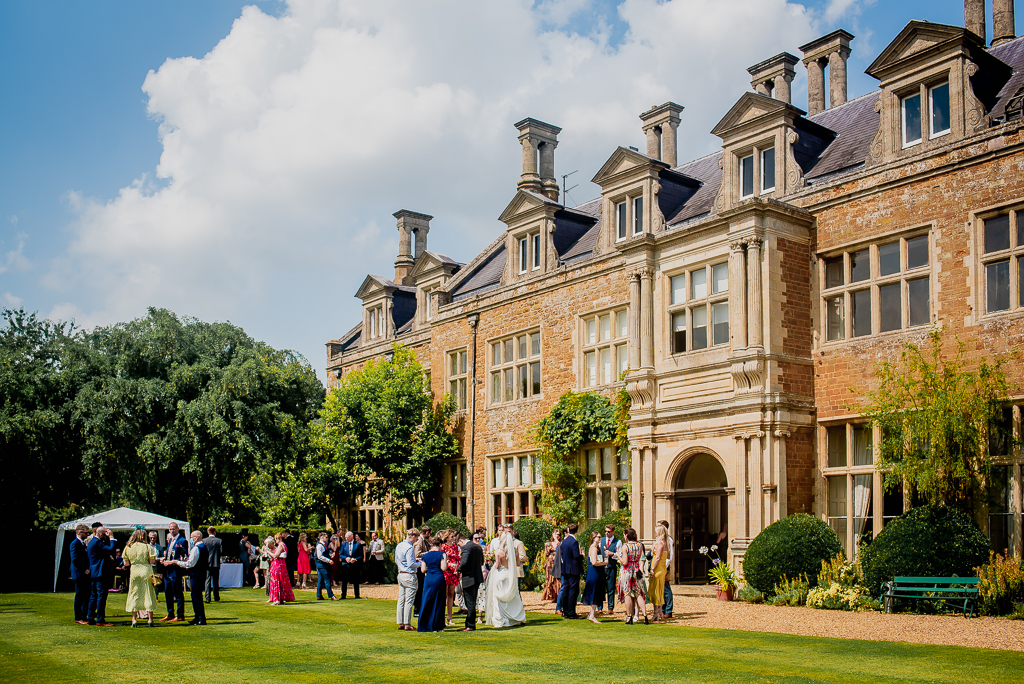 Tommy and Sarah's elegant modern Holdenby House wedding. She wears a minimal strappy dress and he's in a blue check suit. Photographer credit Damien Vickers Photography