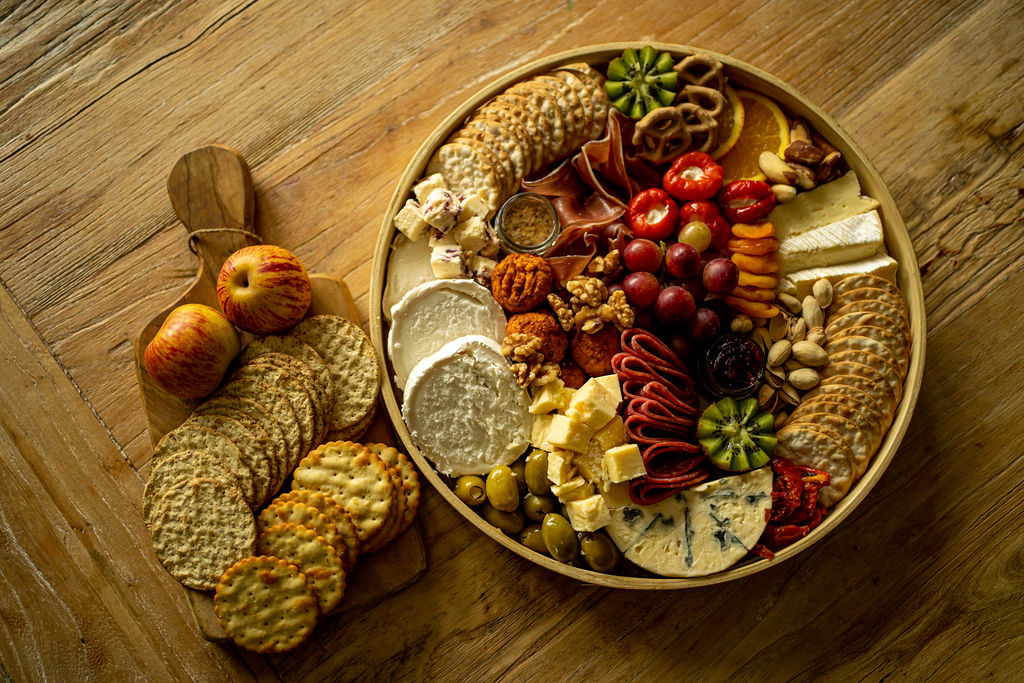 A platter of cold meats, cheeses, crackers and nibbles on a wooden table