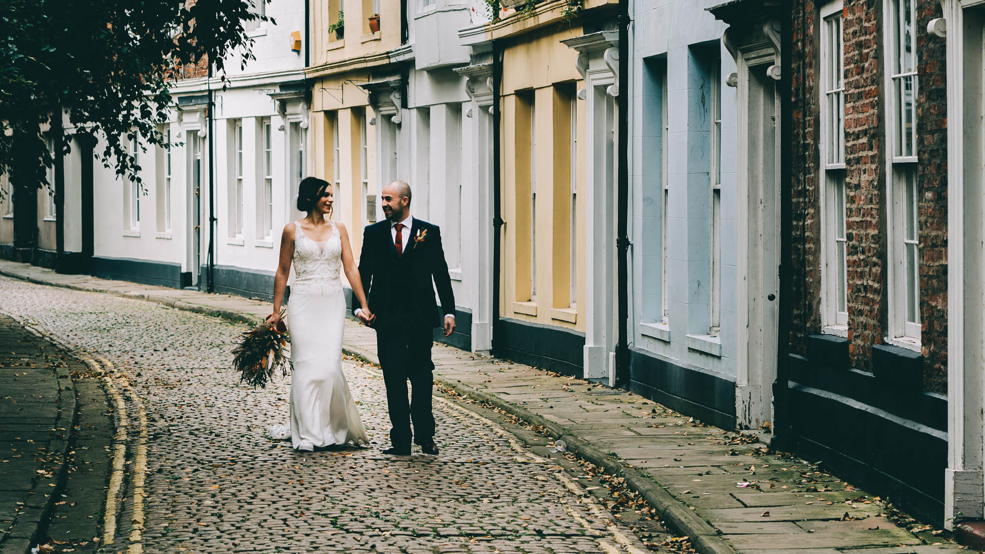 A bride and groom strolling down the cobbled streets of York by Abraham Photography