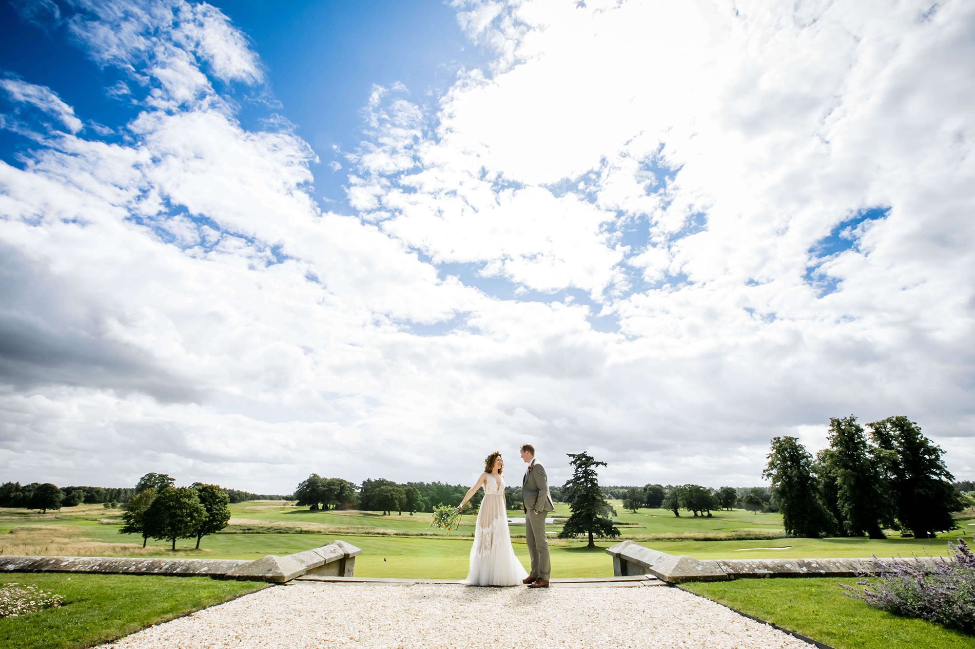 Bride and groom under a wide open blue sky with light clouds, by North East England wedding photographer Erika Tanith