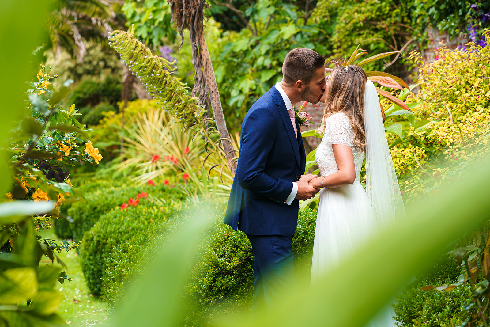Gorgeous greenery surrounds a couple of newlyweds having a smooch! By Tracey Warbey Photography