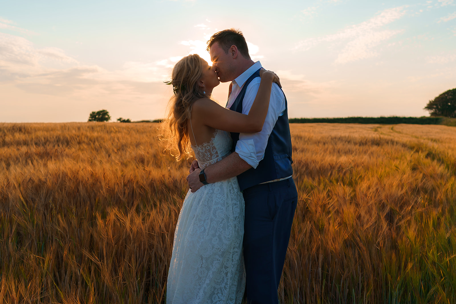Newlyweds kissing in a corn field at golden hour. By Tracey Warbey Photography