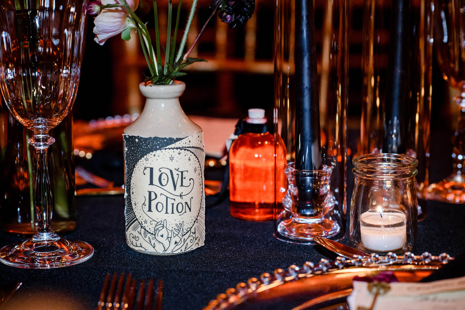 Gothic style wedding table with a quirky halloween style love potion bottle as a flower vase