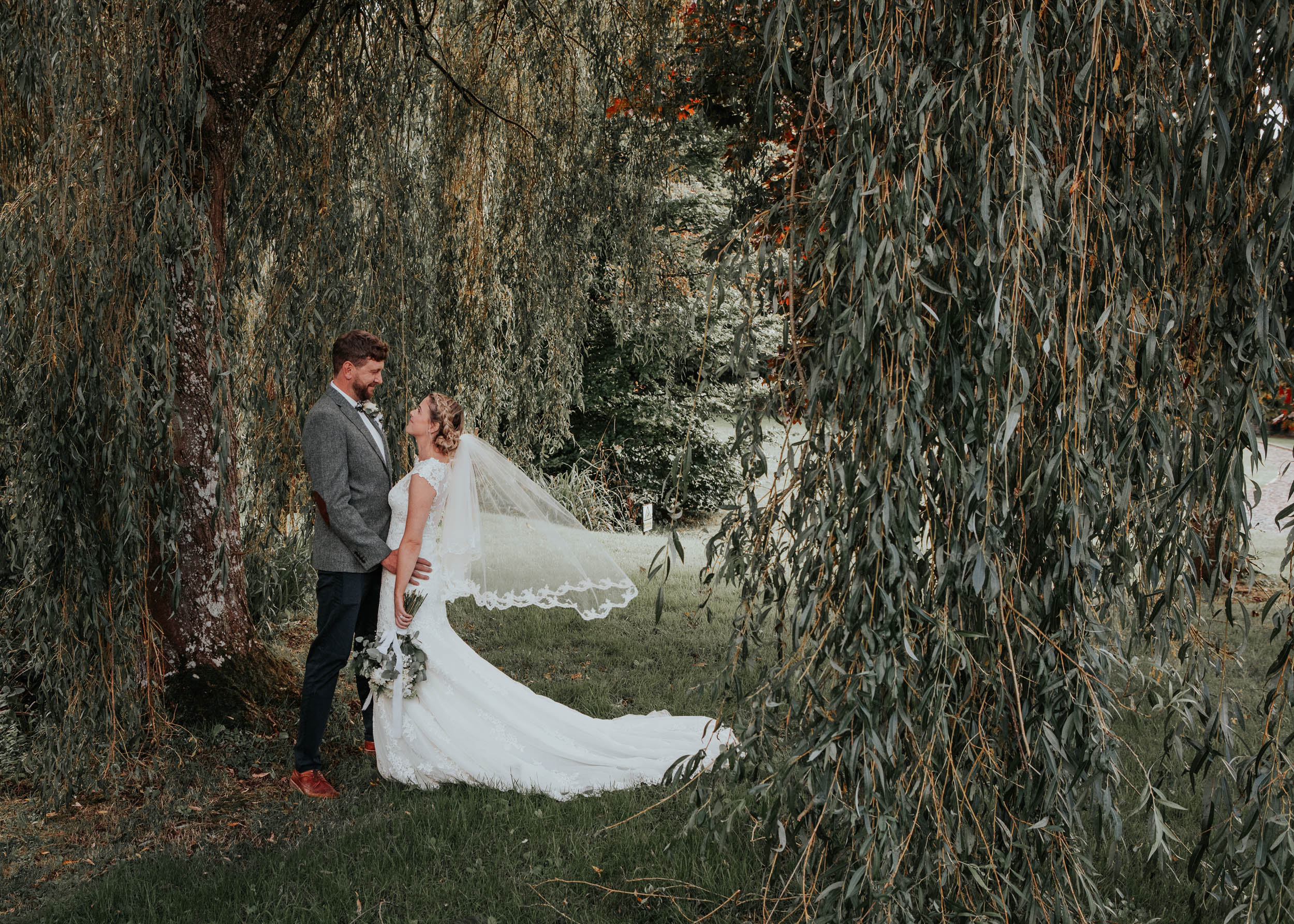 Bride and groom surrounded by mature willow trees