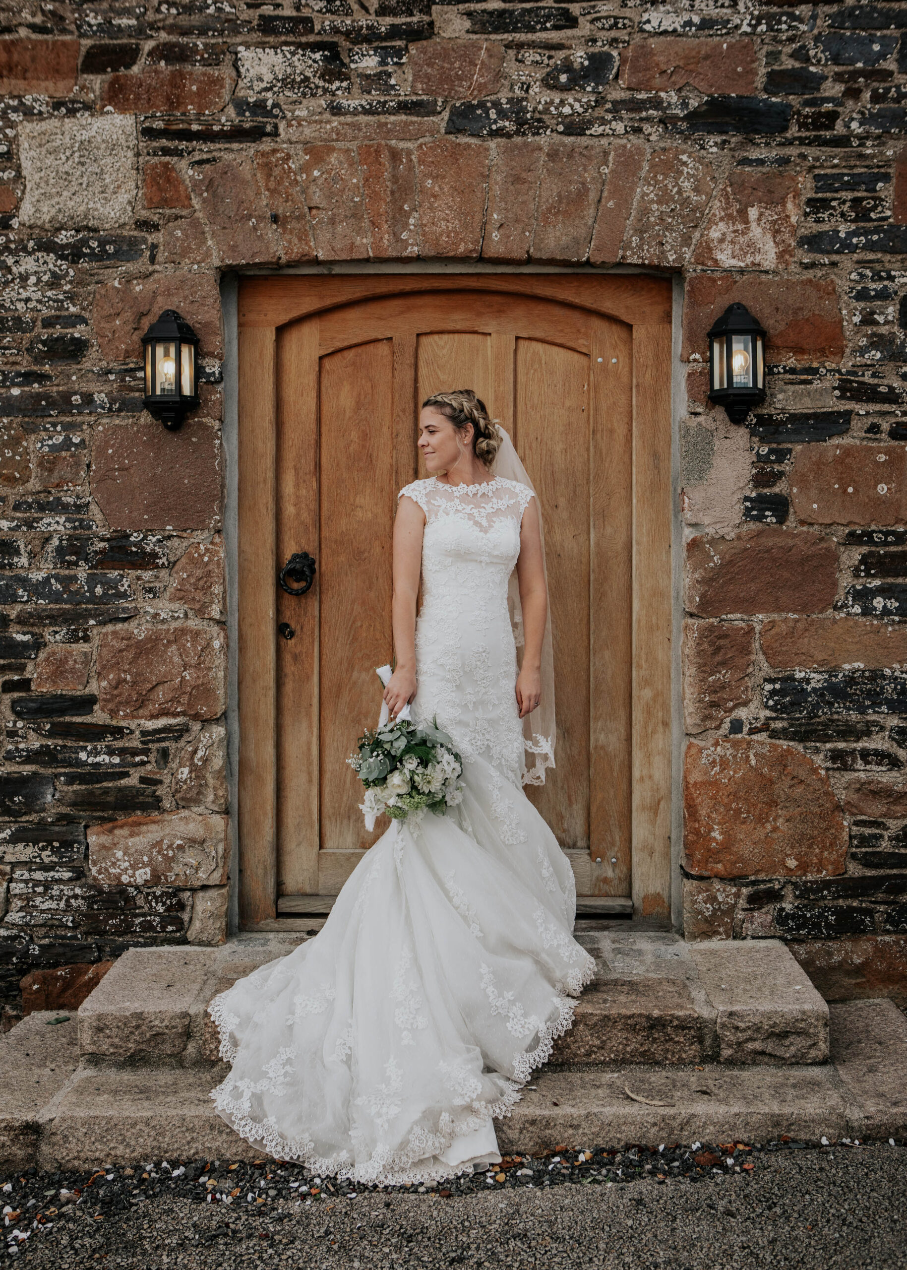 Bride in a doorway with her bouquet held by her side