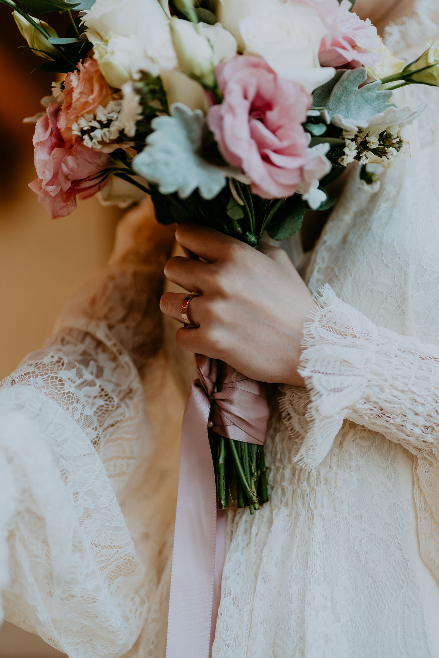 Close up of bride's hand holding a bouquet with pink lisianthks flowers