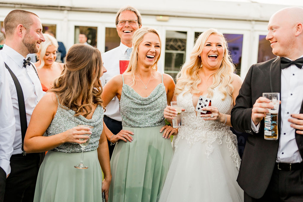 A bride and her bridesmaids laugh as they're astonished by UK wedding magician Close-Up Chris