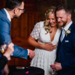 A bride and groom smile as they watch a sleight of hand trick performed by UK wedding magician Close-Up Chris