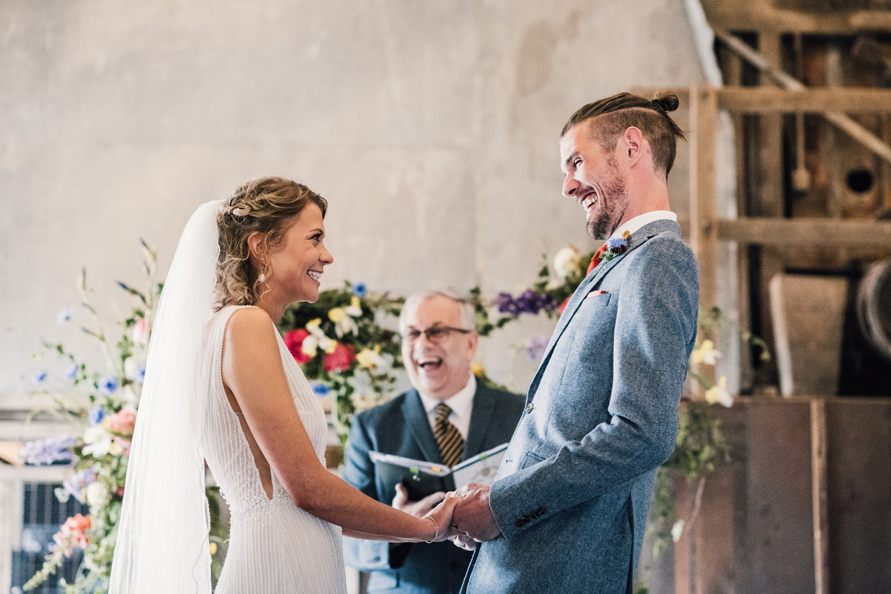 Joyful newlyweds look at each other as the celebrant announces they're married! Damien Vickers Photography