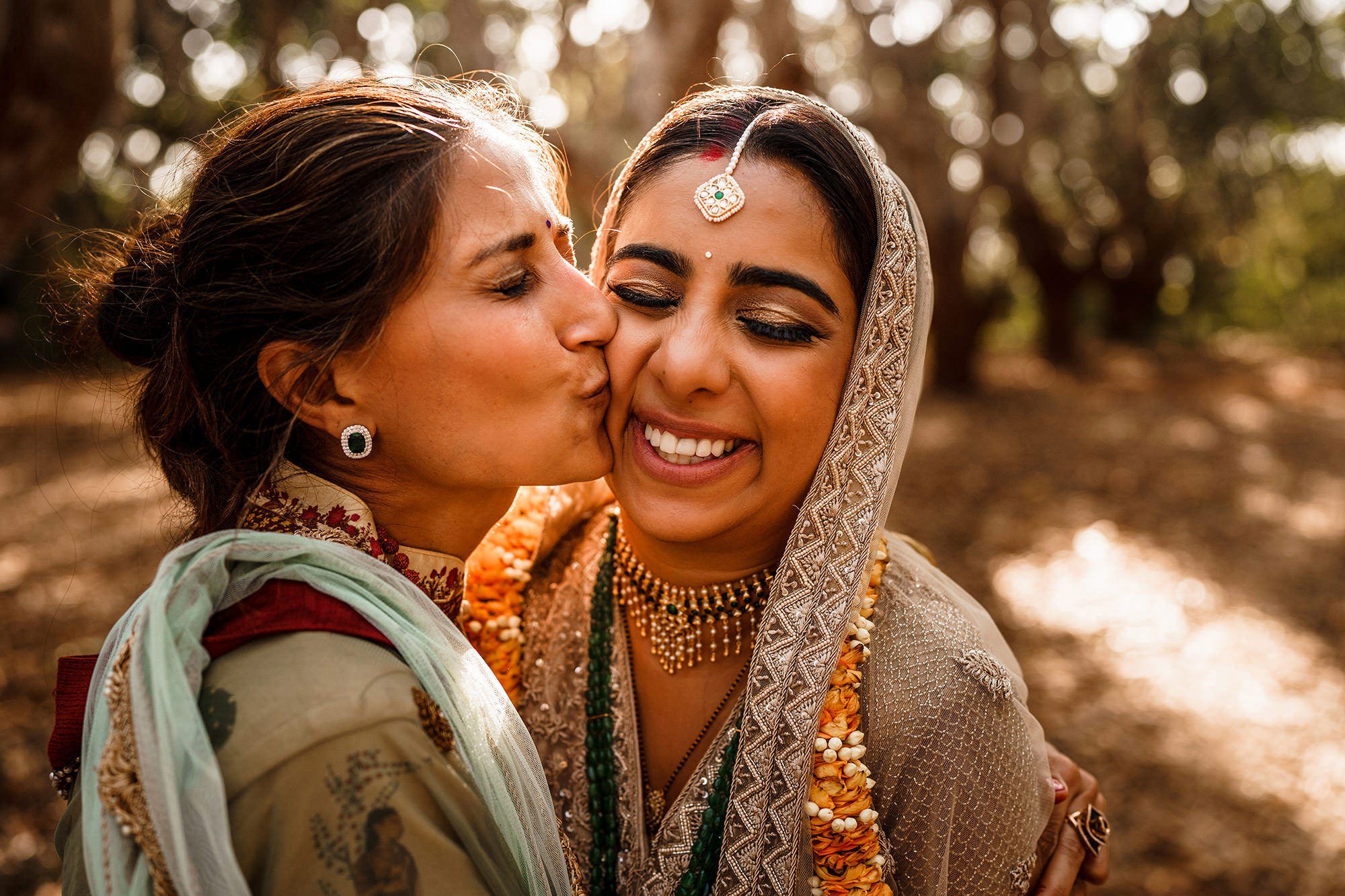 A kiss on the cheek from a wedding guest at an Asian wedding. Image by Stephen Walker Photography