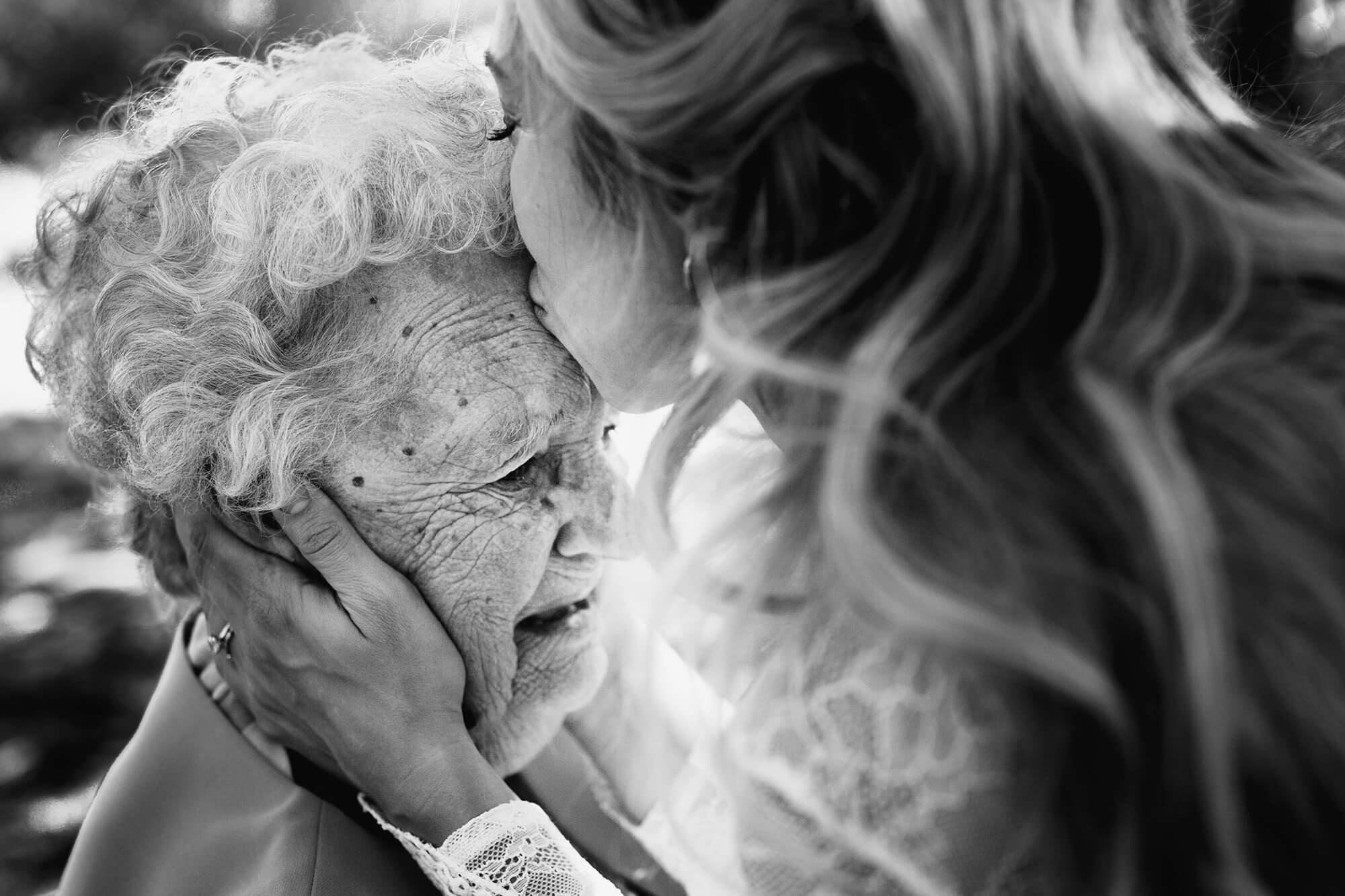 A bride kisses her grandmother on the forehead in a beautiful close up black and white wedding image. Stephen Walker Photography