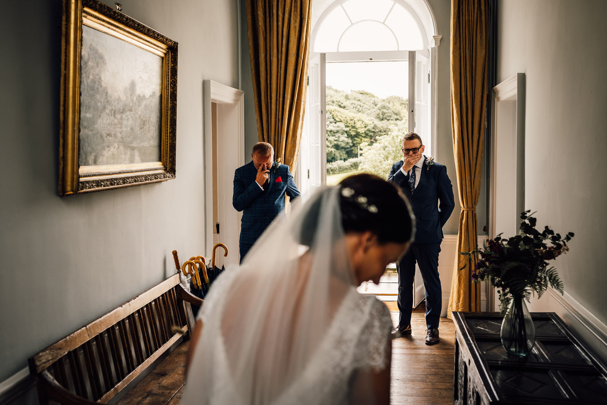 A bride's family who could be her dad and brother are overcome with emotion as they see her in her dress for the first time. By Chris Armstrong Photography in Cornwall