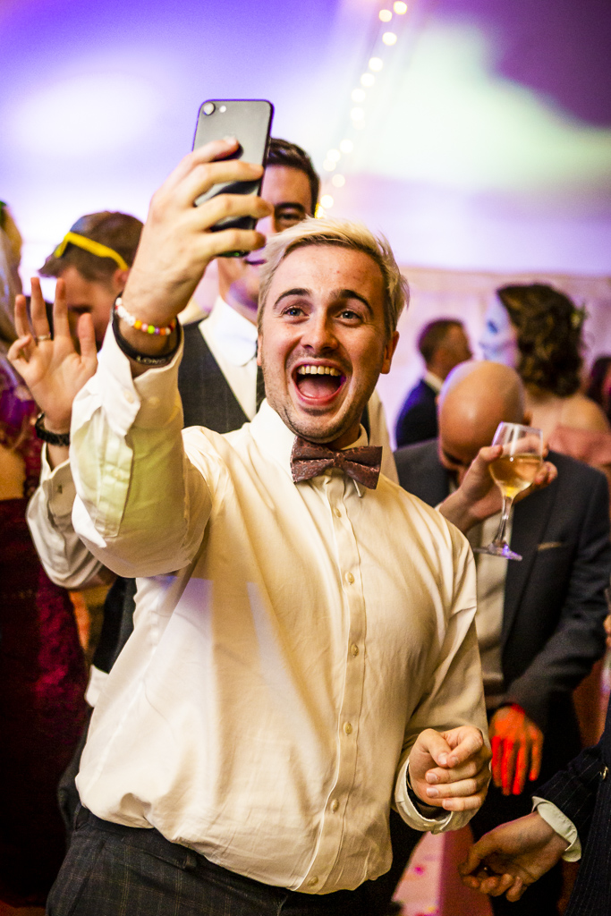 Taking a selfie on the wedding dance floor! This groom or guest is looking fab in a bowtie and smiling for the camera! With Ross Willsher Photography