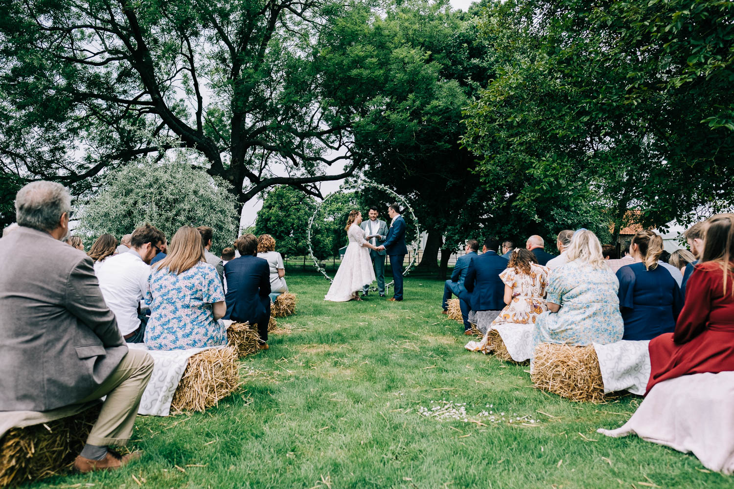 Boho style whimsical wedding on a lawn with guests seated on hay bales. By Lincolnshire wedding photographer 166 Photography