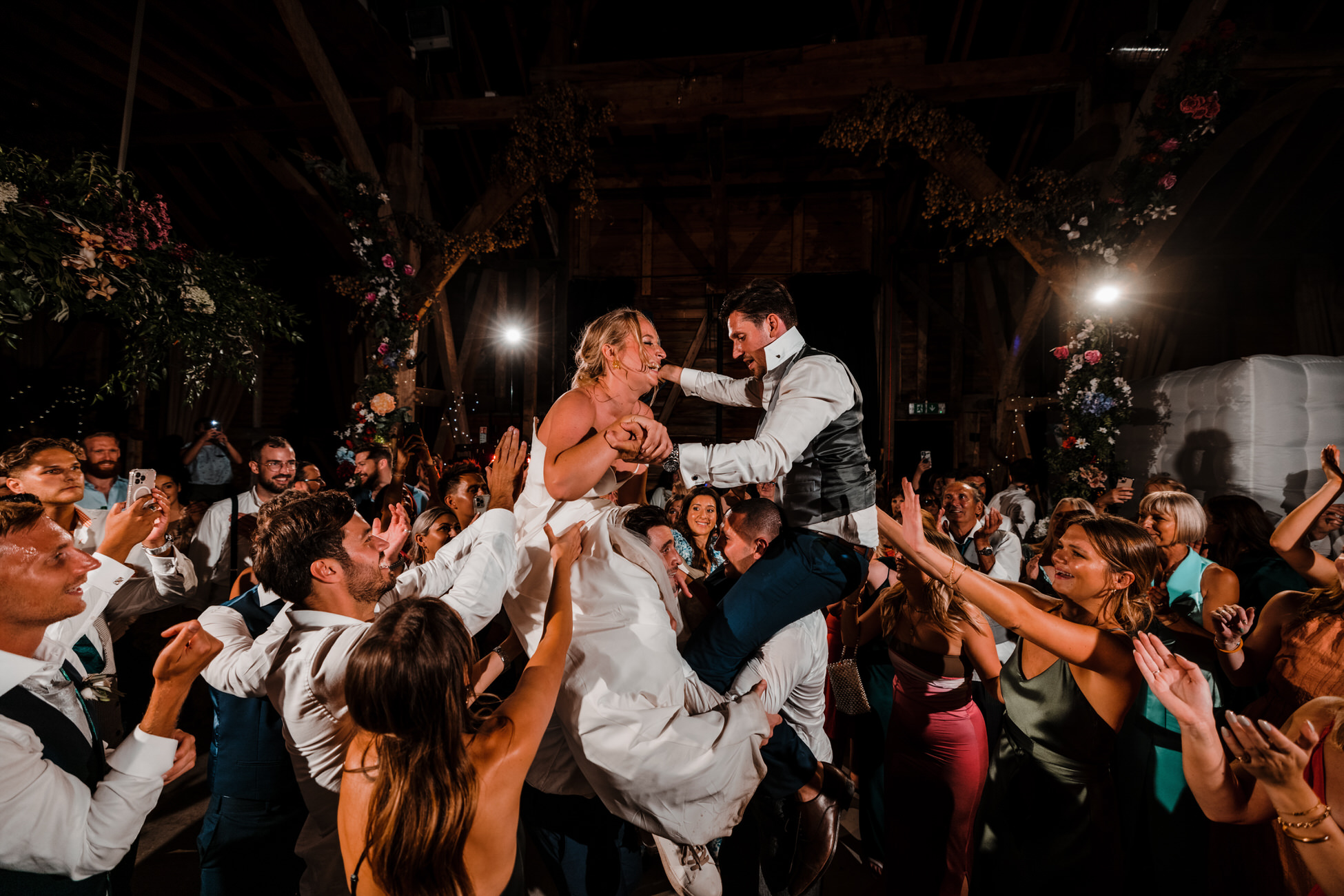 A bride and groom are lifted onto their friends' shoulders in the middle of a packed dance floor! Photo by Tom Hodgson