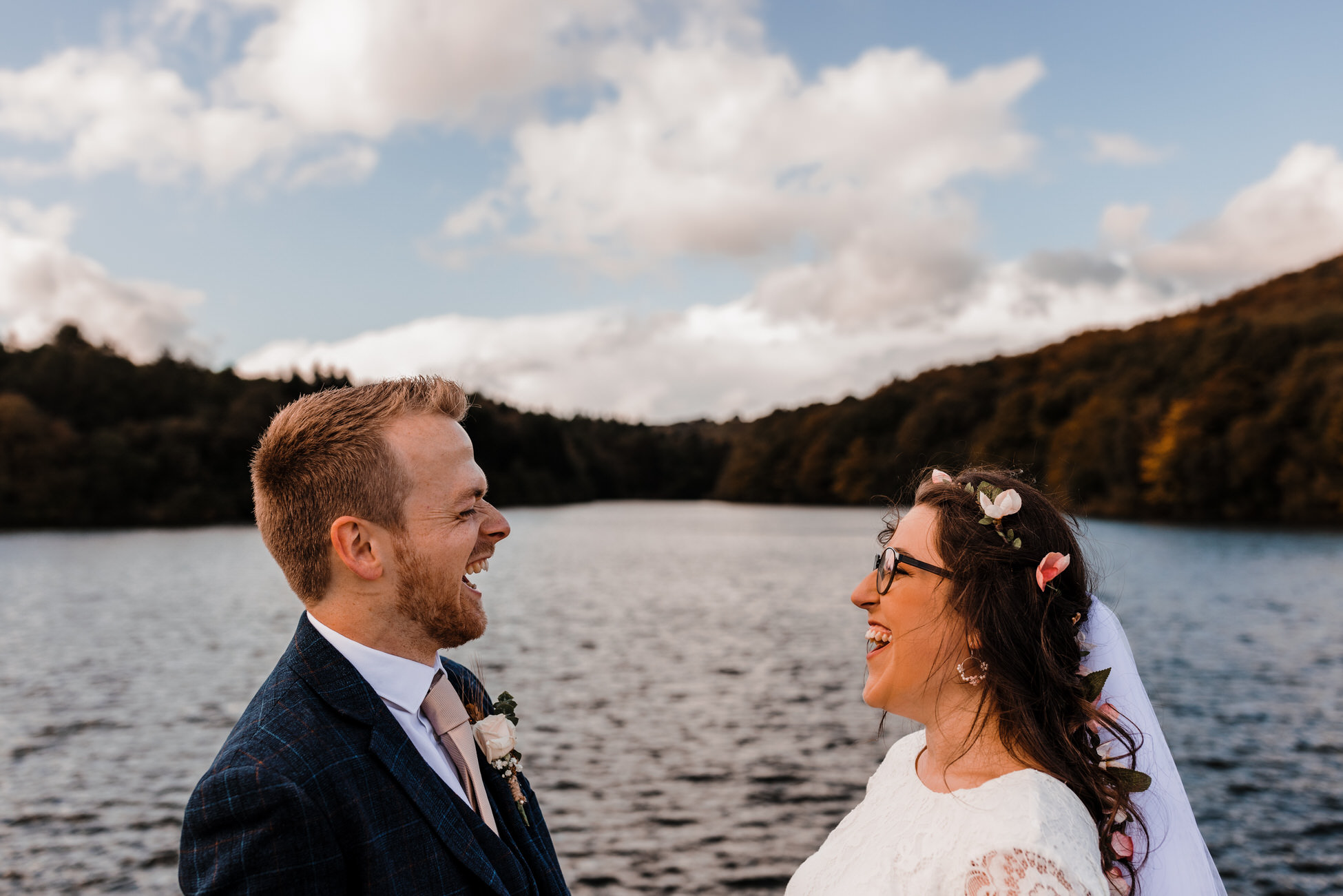 Owen and Emily look super happy in this relaxed photo from their wedding day, taken by a reservoir or lake. By Tom Hodgson Photography