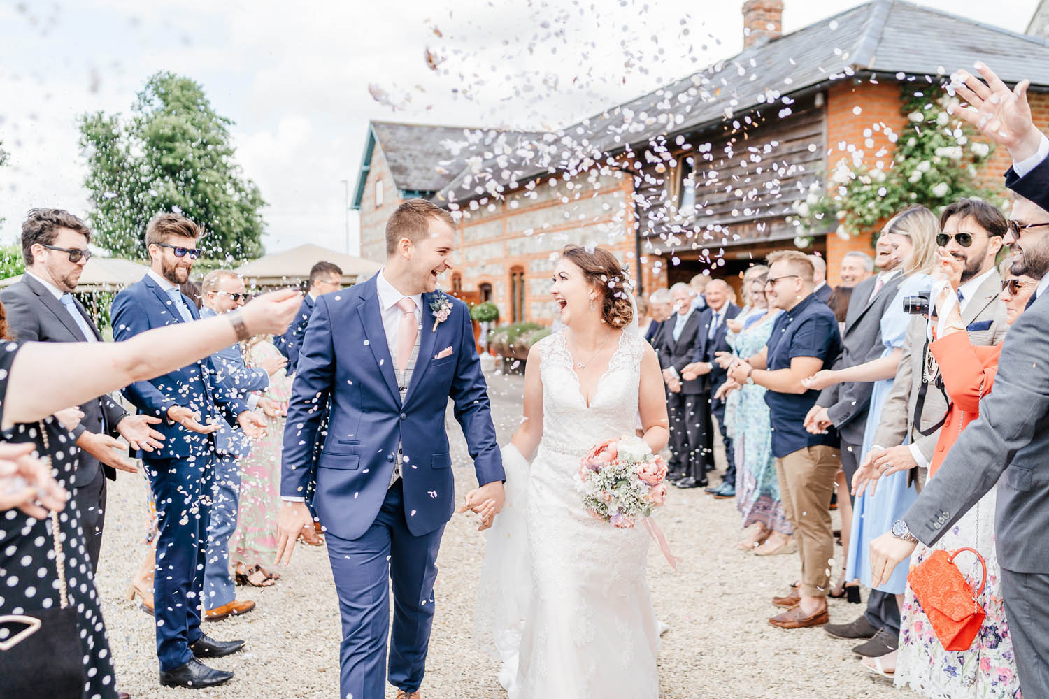 Bride and groom turn to each other and laugh as guests throw confetti on their wedding day. By Rebecca Casey Photography at The Manor Estate