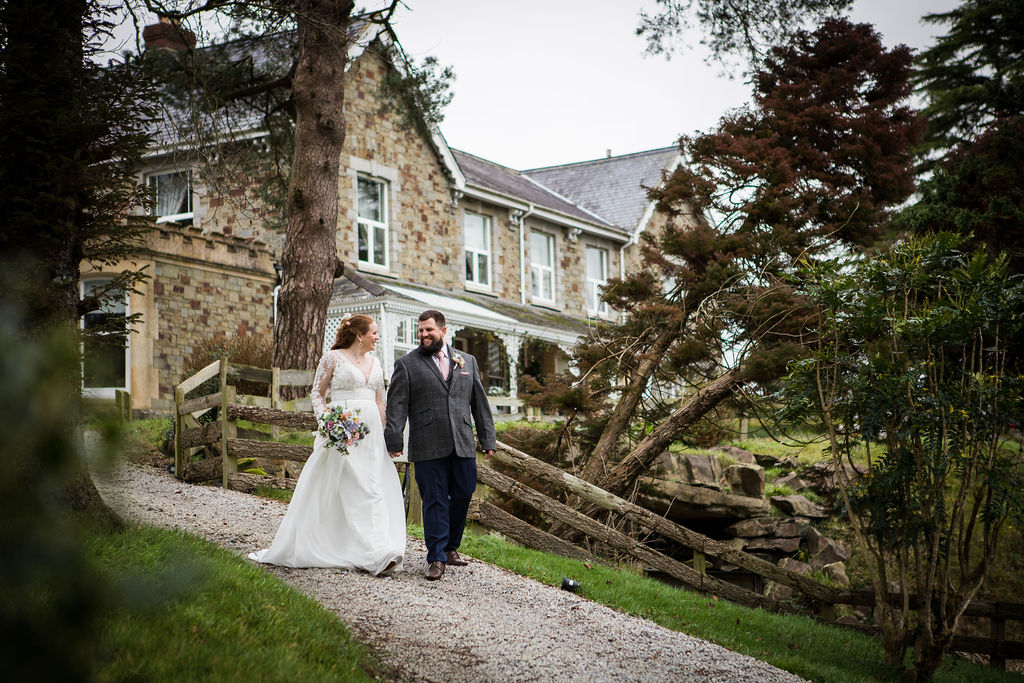 A couple walk hand in hand down the path at Little Silver Weddings in Devon