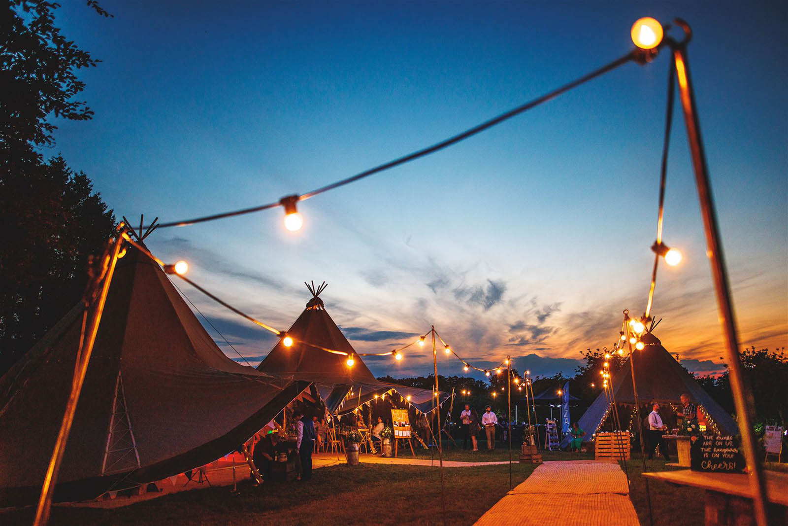 Tipis at sunset with festoon lighting, from the Orchard at Munsley in Herefordshire