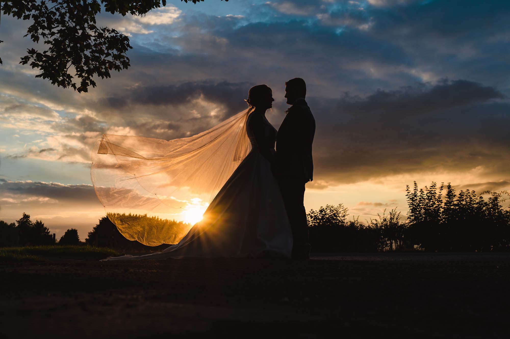 Sunset wedding photo with the sun light filtering through the bride's veil