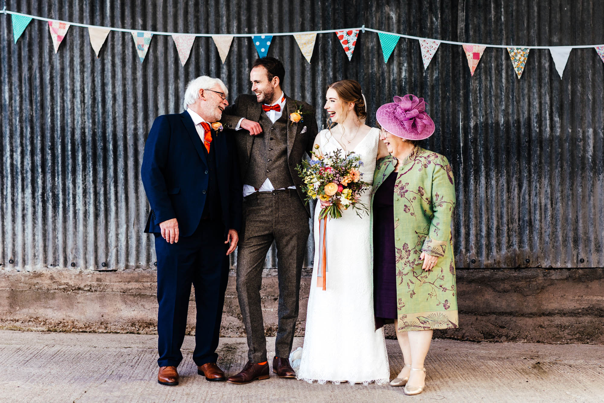 informal wedding group photo of a groom and bride with family members. They're relaxed and having a giggle together so the shot doesn't look too formal. By Hannah Hall Photography