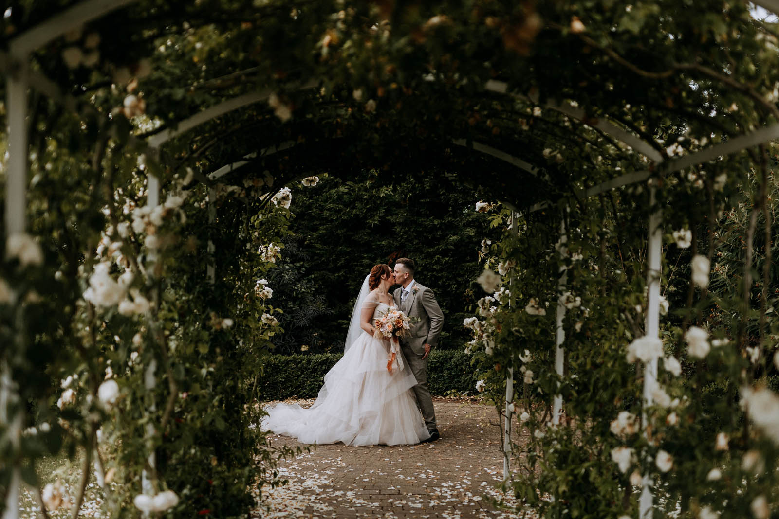 Bride and groom under rose archways at The Ferry House