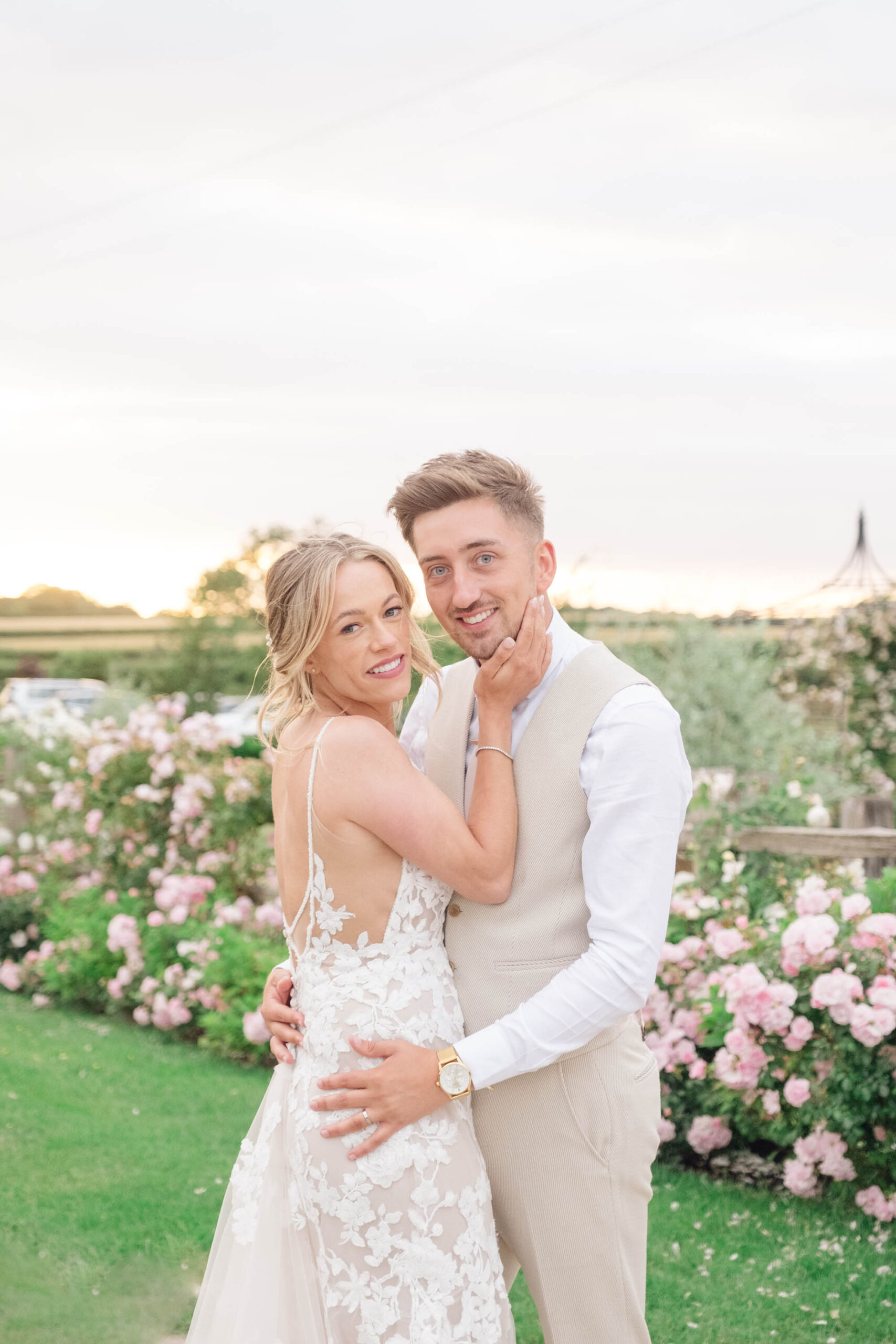 Romantic, light and airy posed wedding photo of a groom and bride with a pink rose border behind them. Taken by Staffordshire wedding photographer Jordan Fox Photography