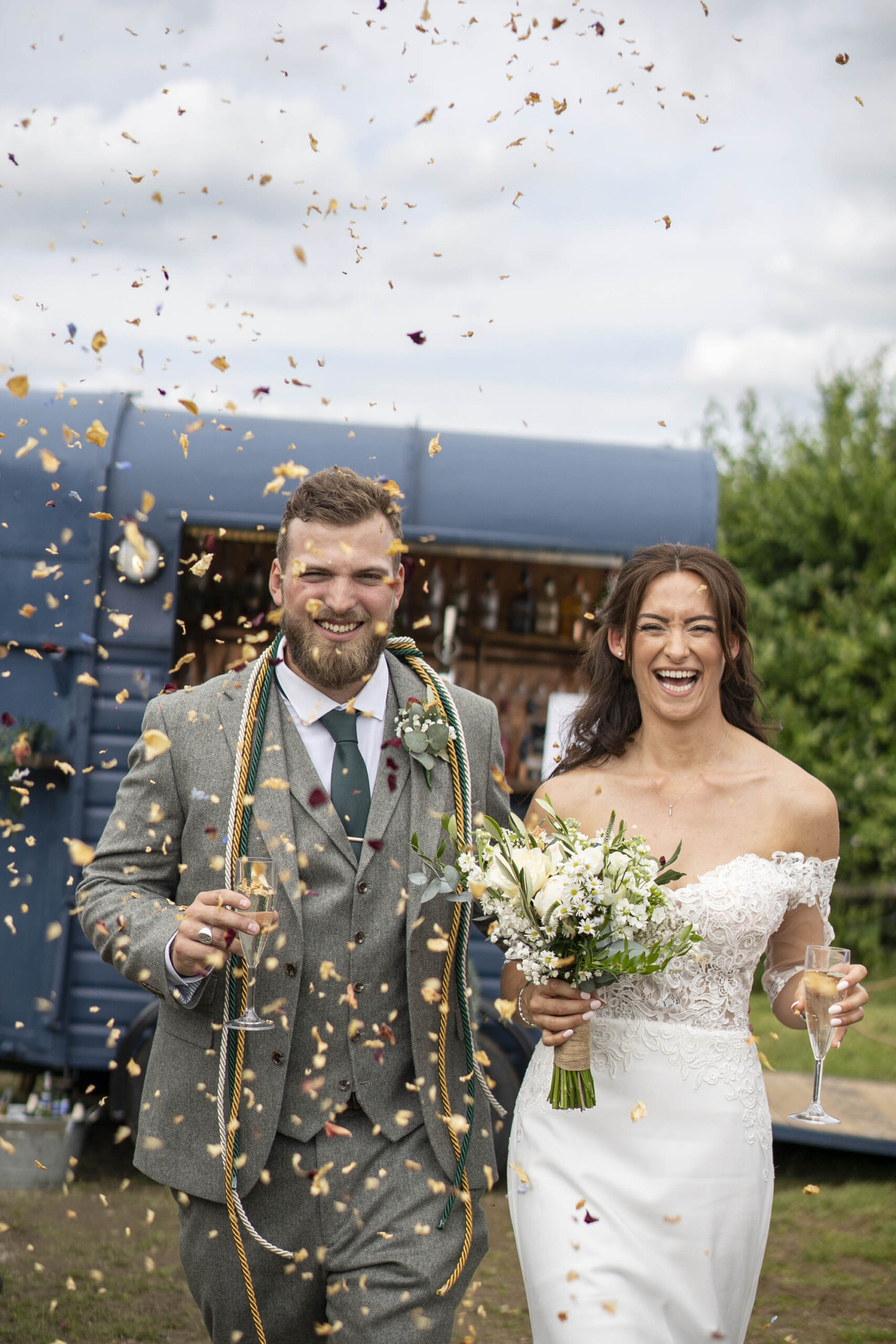 Groom and bride walking towards the camera through confetti - image by Jodie Cooling Photography