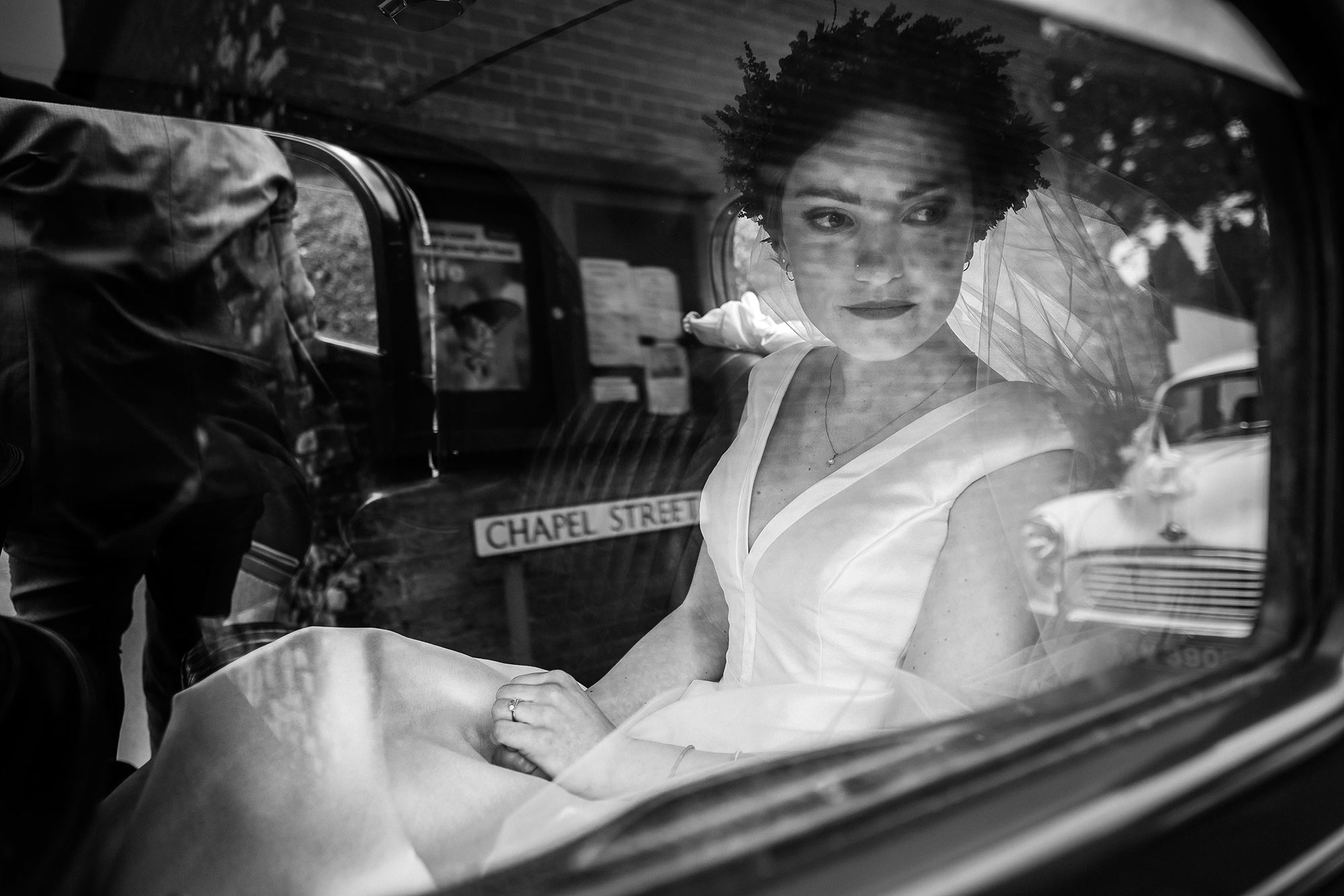 Dreamy black and white wedding day photograph of a bride through a car window. By Smiling Tiger Studios