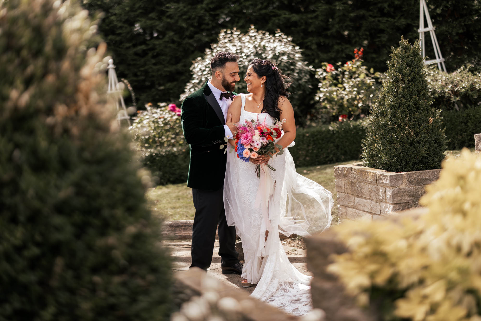 Newlyweds at The Ferry House in Kent. She's holding colourful flowers and the sun is shining. By Daniel Luke Photography