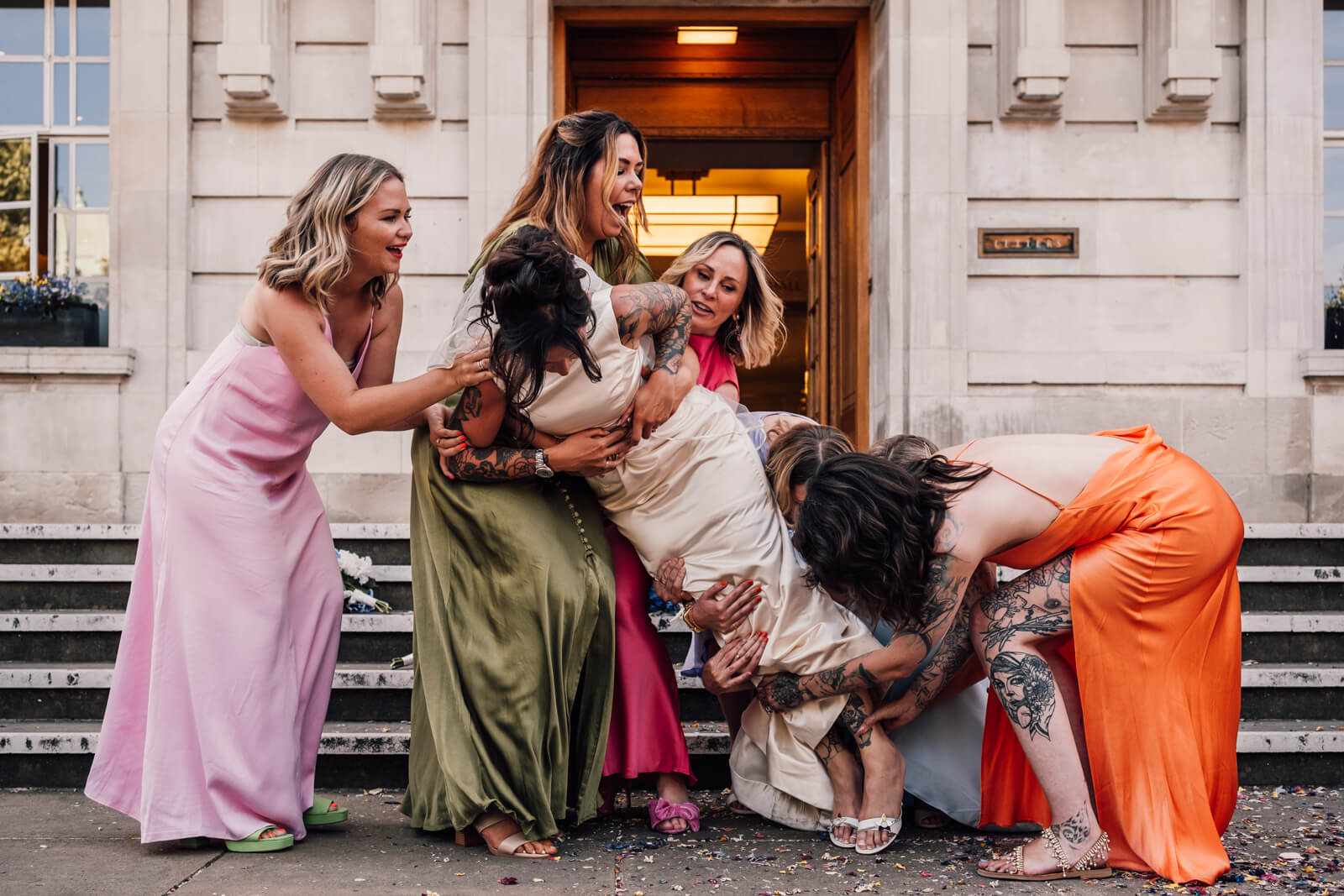 Bride being picked up by bridesmaids and it's not going well but it's hilarious. By Emis Weddings London