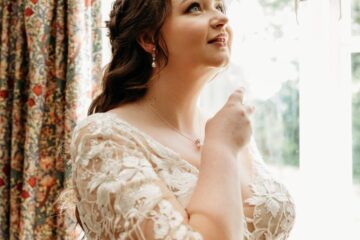 bride spraying perfume by a window