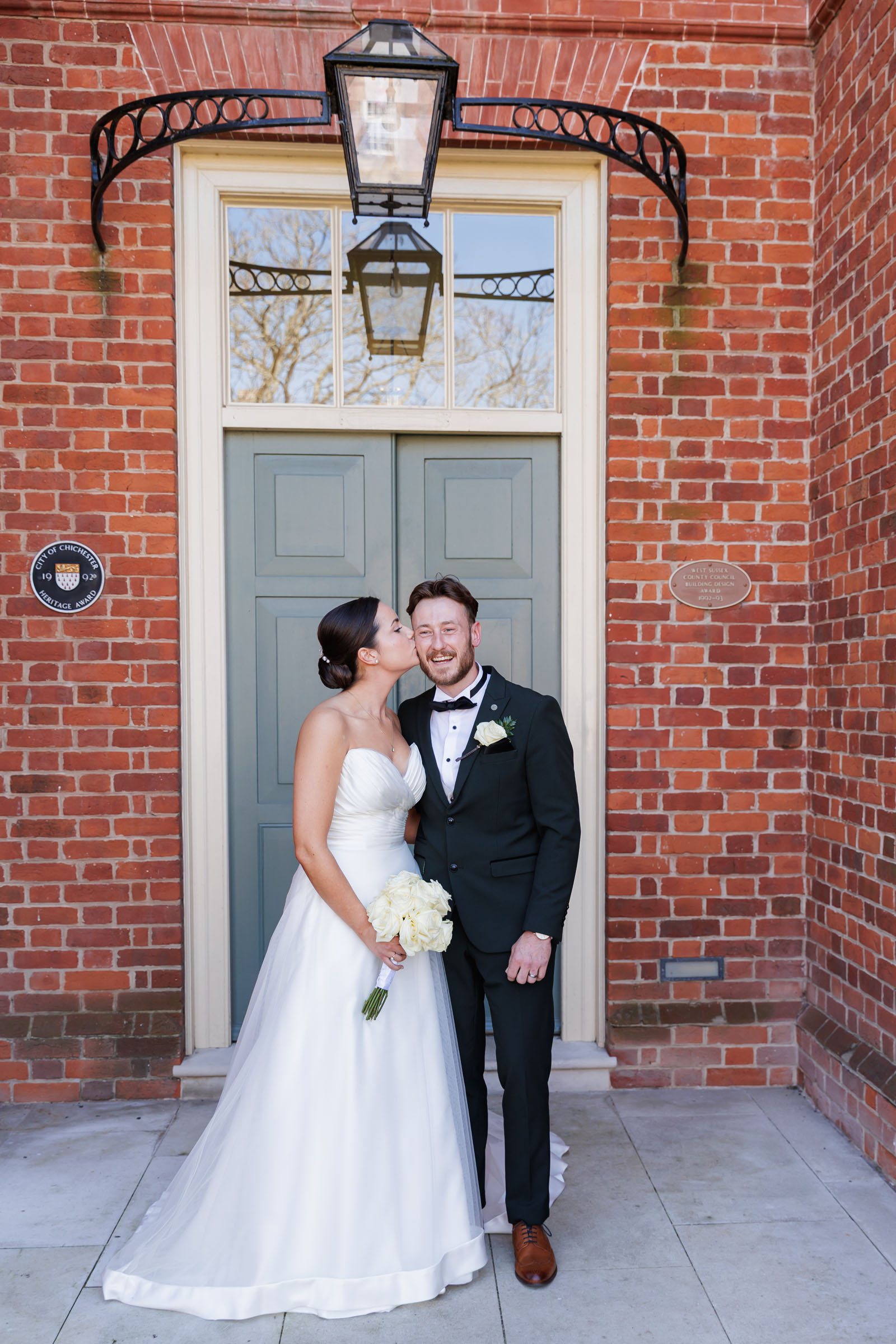 groom and bride posing for a photograph outside the door of their wedding venue