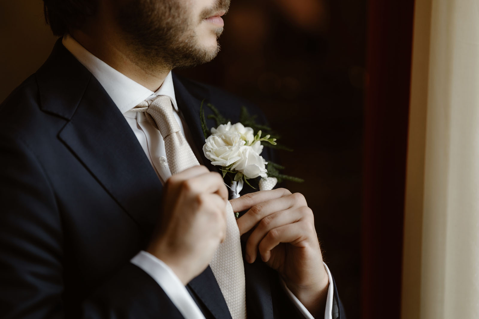 Man straightening his tie, getting dressed for a wedding