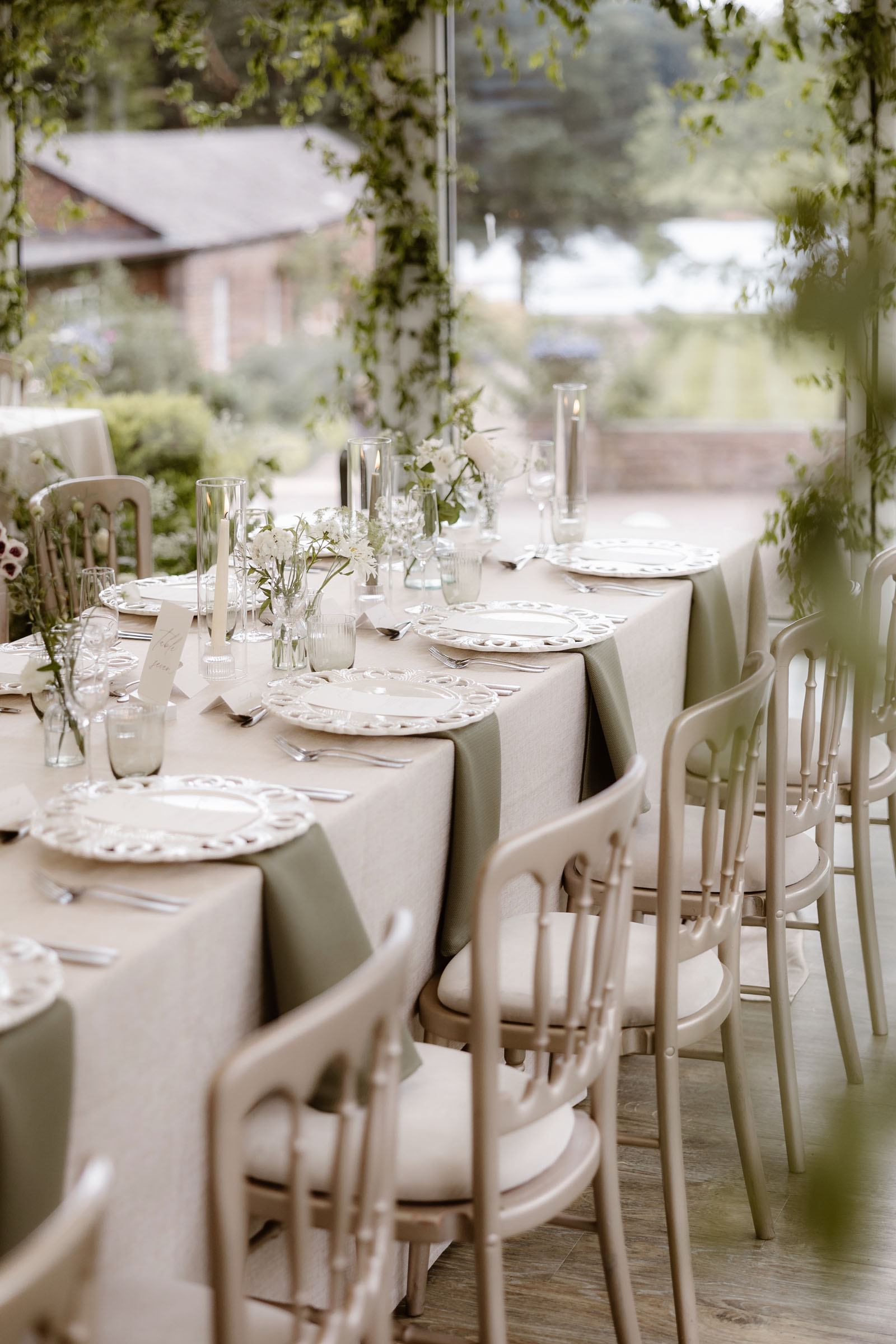 Super elegant wedding tables in a natural colour palette surrounded by soft greenery and with delicate stems dressing tables