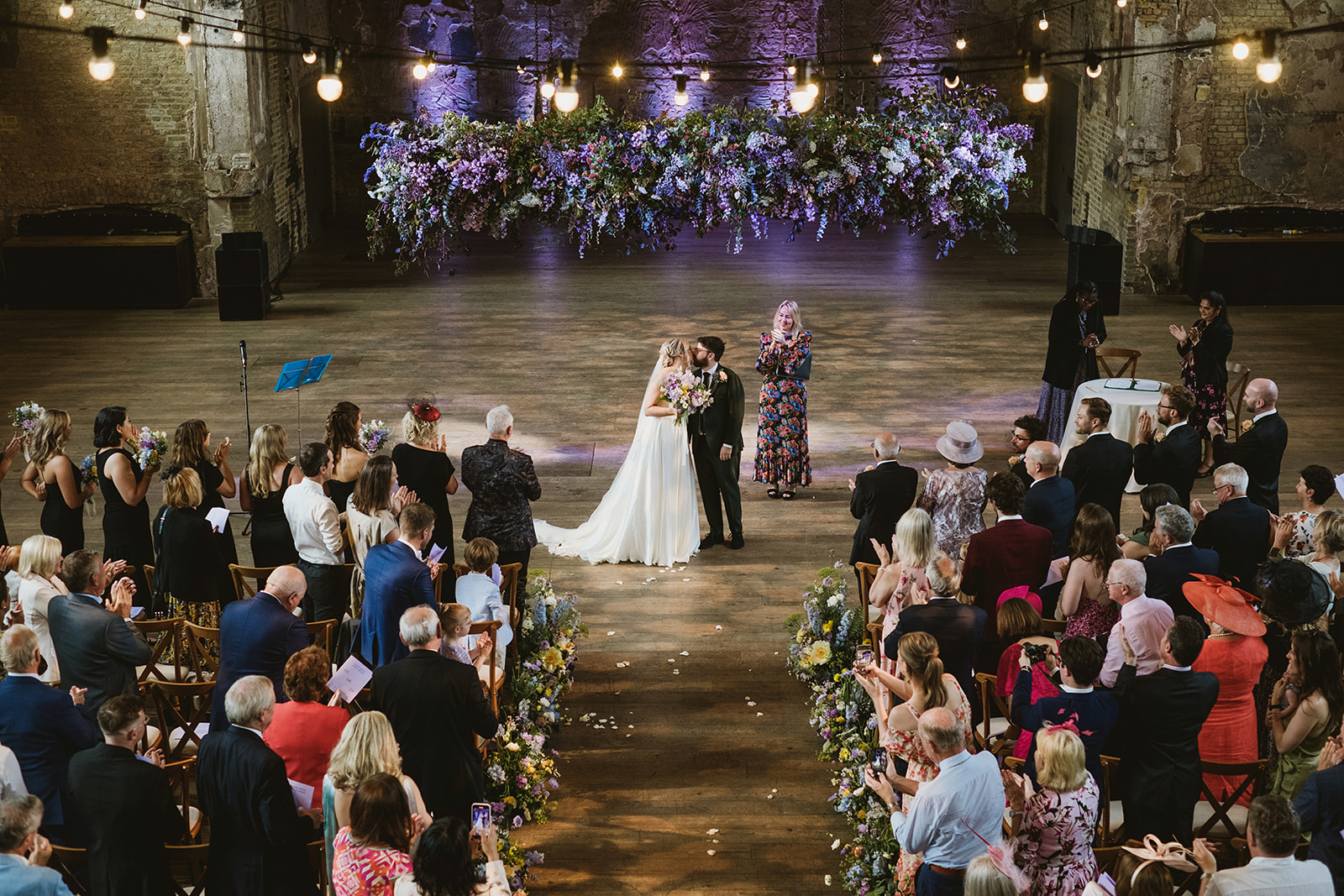 Layered wedding photography by York Place Studios - a bride waves a fan while guests talk behind her and a little boy peeks from behind his mum's skirt